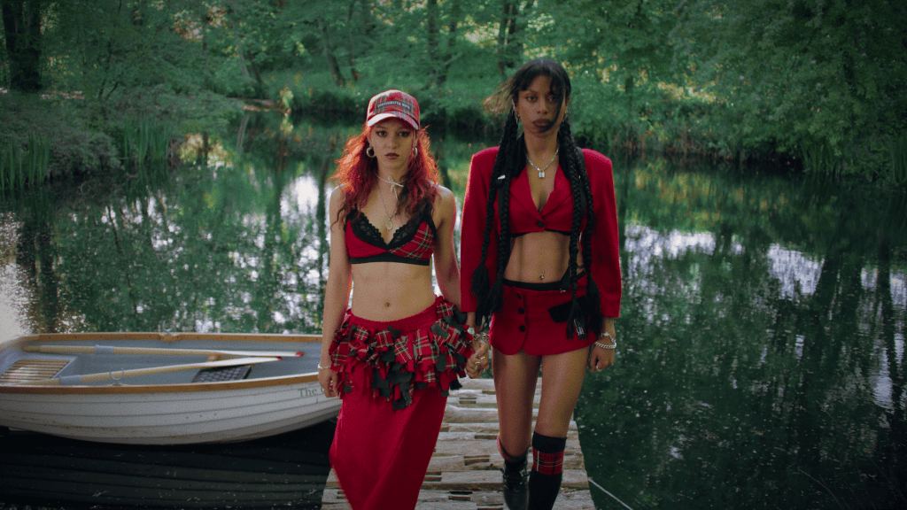 Nova Twins - Photo Credit - Fin Frew - Two women in red outfits standing on a dock