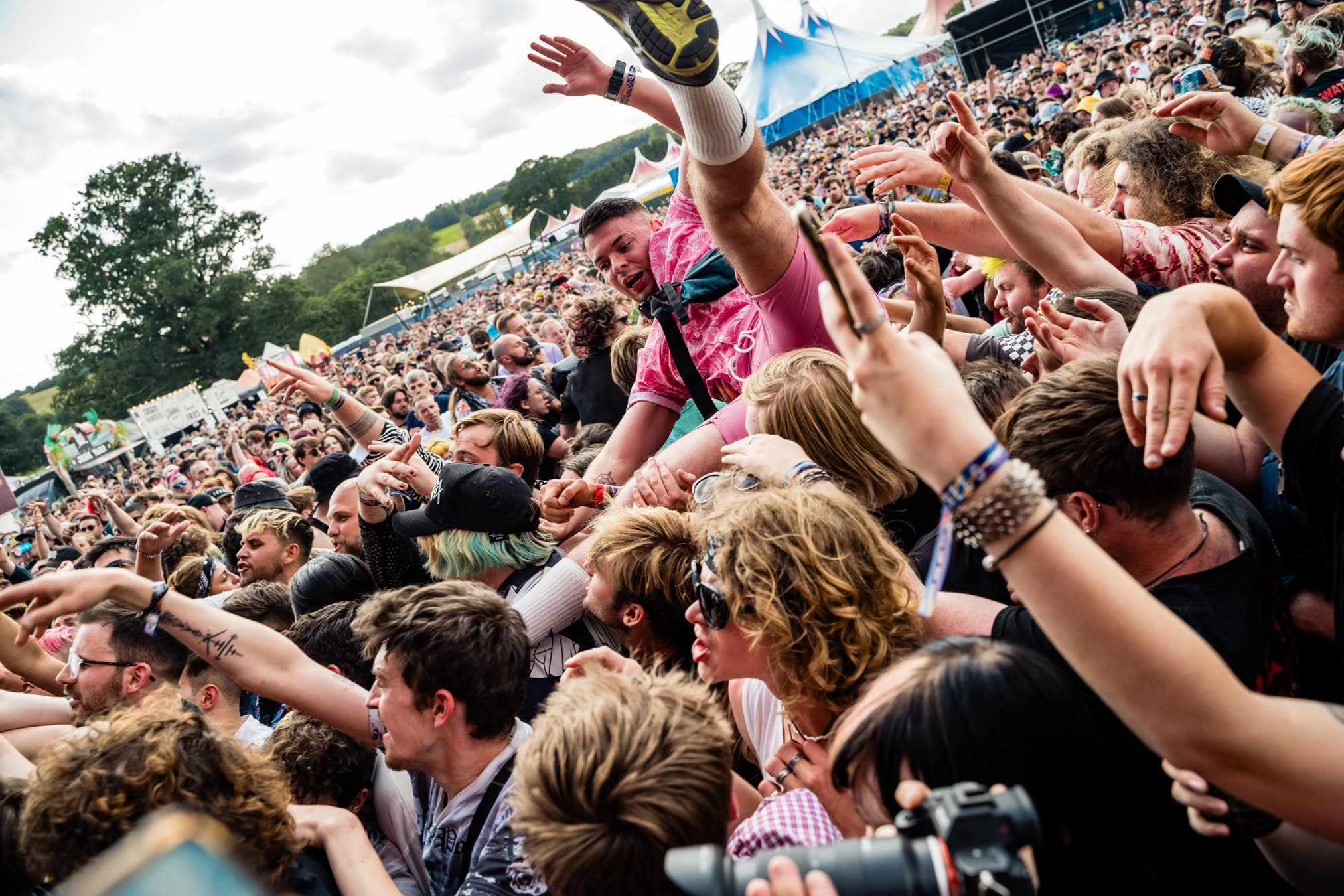 Crowd surfer carried over a packed crowd on a sunny day at 2000trees Festival 2023, Upcote Farm