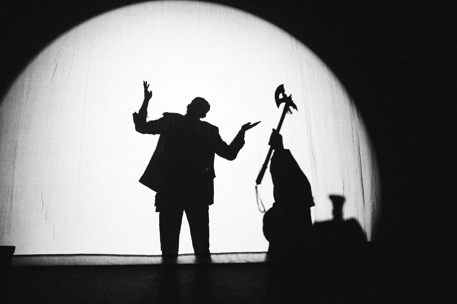 The stage announcer and an axe-wielding figure in silhouette behind the white screen before Creeper's set