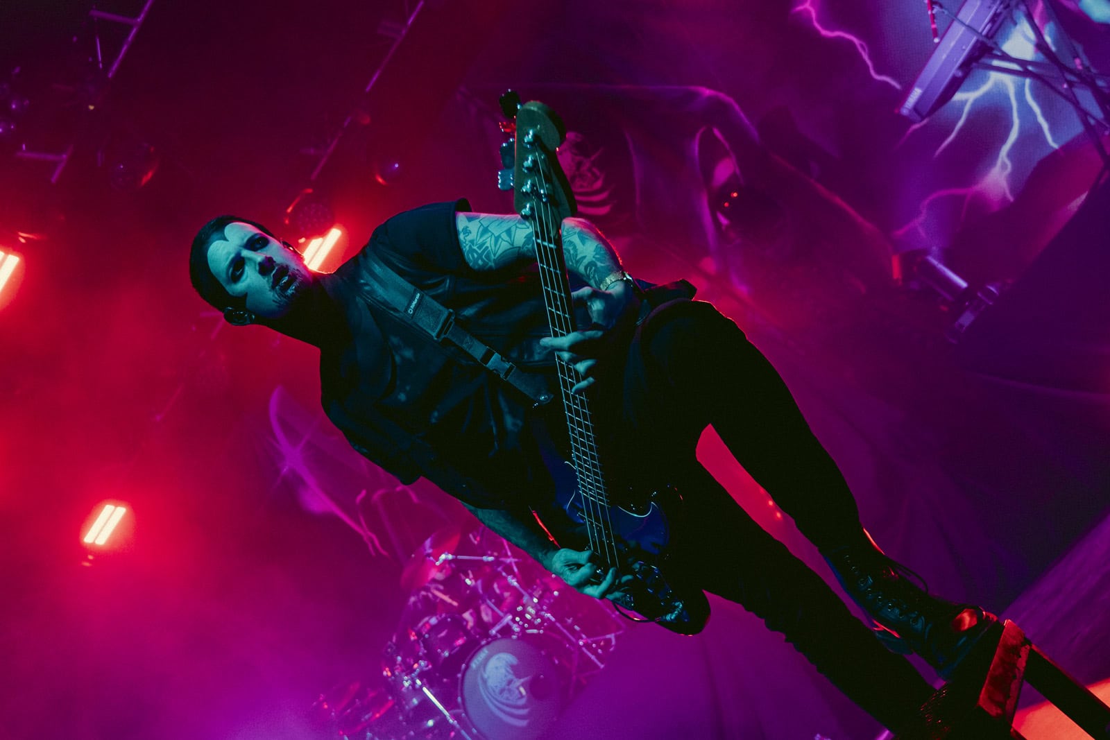 A Creeper guitarist playing under pink and purple light, shot from below