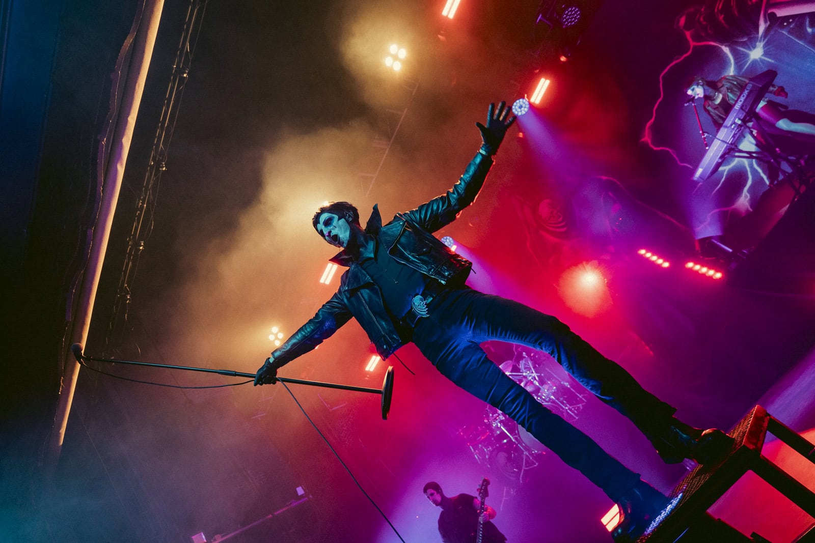 Creeper's Will Gould standing on a riser with his arm outstretched through red smoke